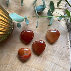 Back to school blog, Carneool hart met diep rode en oranje tint, Carneool Hart op een houtentafel in kaarslicht