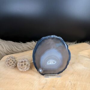 Gepolijste natuurlijke agaatschijf met unieke kristallagen en patronen, getoond op een standaard als decoratieve edelsteen.