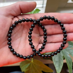 Onyx armband met elastische band en krachtige uitstraling, Close-up van Onyx armband met zwarte stenen, symbolen van bescherming, Onyx armband voor zelfvertrouwen en balans, stijlvolle accessoire