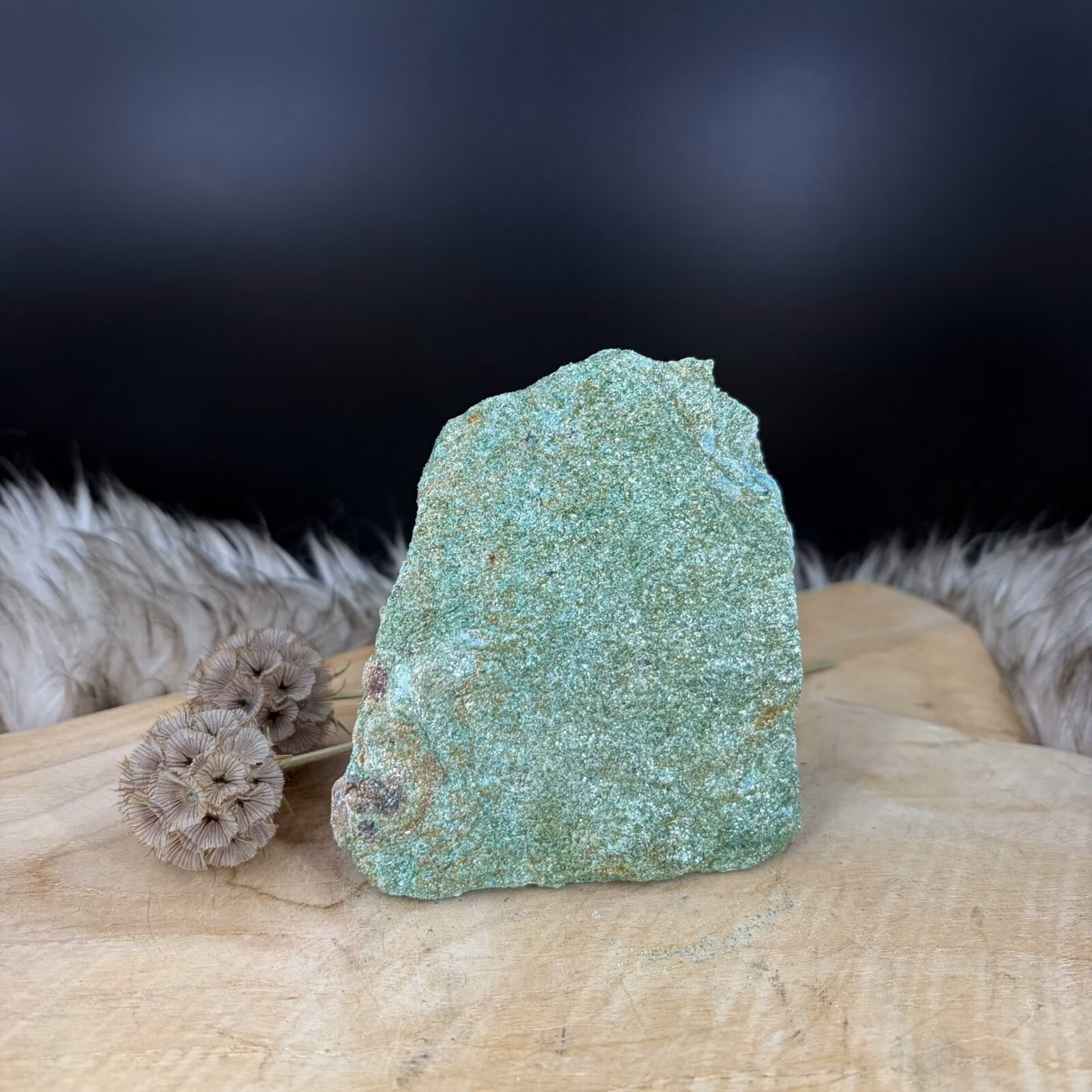 Fuchsiet Cut-Base van 11 cm hoog met een sprankelende groene glans, Detail van de mica schittering in een Fuchsiet van 603 gram, Zijaanzicht van de 4 cm diepe Fuchsiet op een vlakke voet, Groene Fuchsiet Cut-Base op een houten plank in een lichte kamer.
