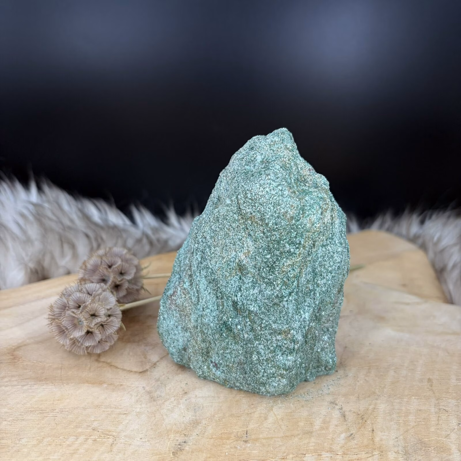 Fuchsiet Freeform van 10 cm hoog met een sprankelende groene kleur, Detail van de glinstering in een Fuchsiet van 506 gram, Zijaanzicht van de 5 cm diepe Freeform Fuchsiet met mica schittering, Groene Fuchsiet op een houten ondergrond in een sfeervol interieur.