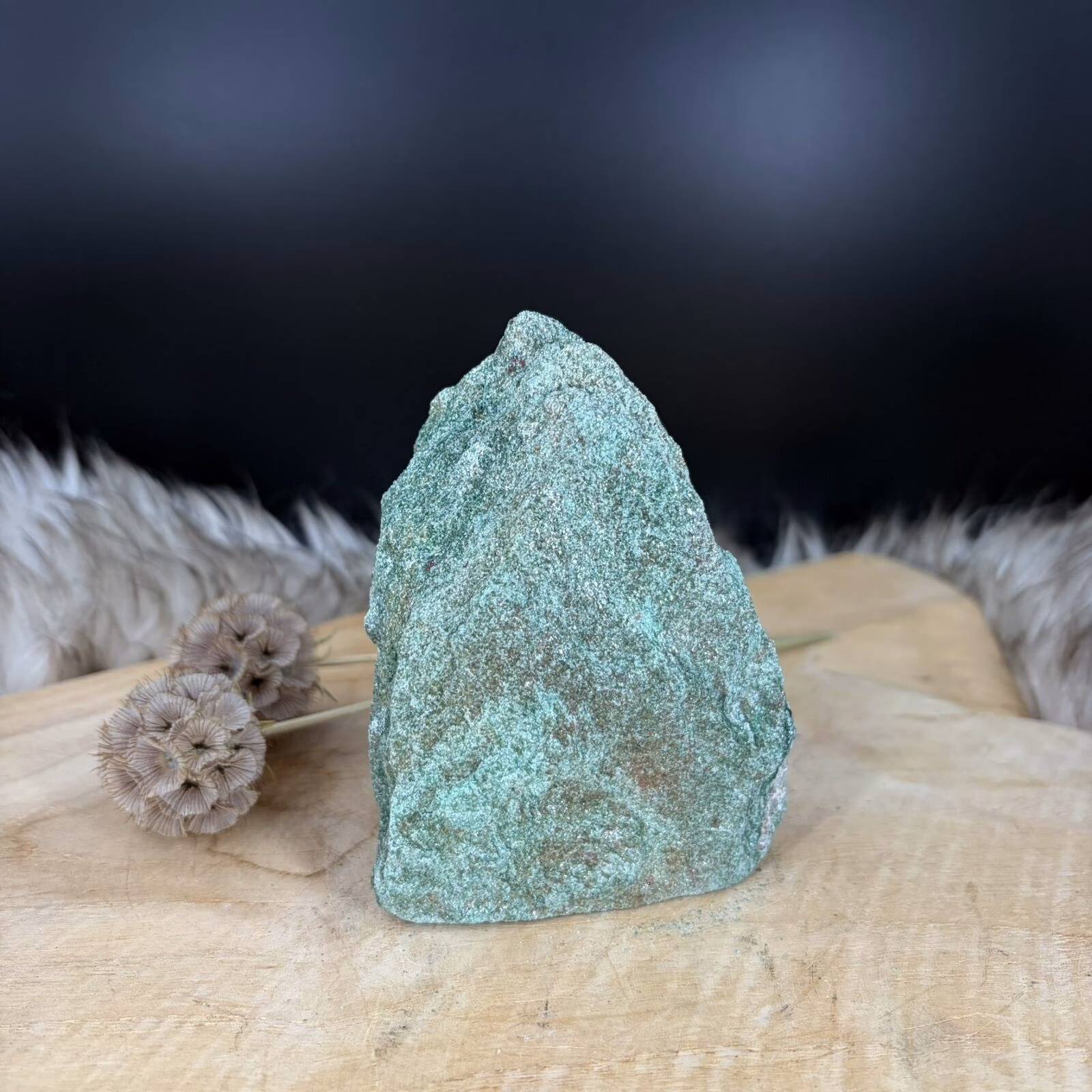Fuchsiet Freeform van 10 cm hoog met een sprankelende groene kleur, Detail van de glinstering in een Fuchsiet van 506 gram, Zijaanzicht van de 5 cm diepe Freeform Fuchsiet met mica schittering, Groene Fuchsiet op een houten ondergrond in een sfeervol interieur.