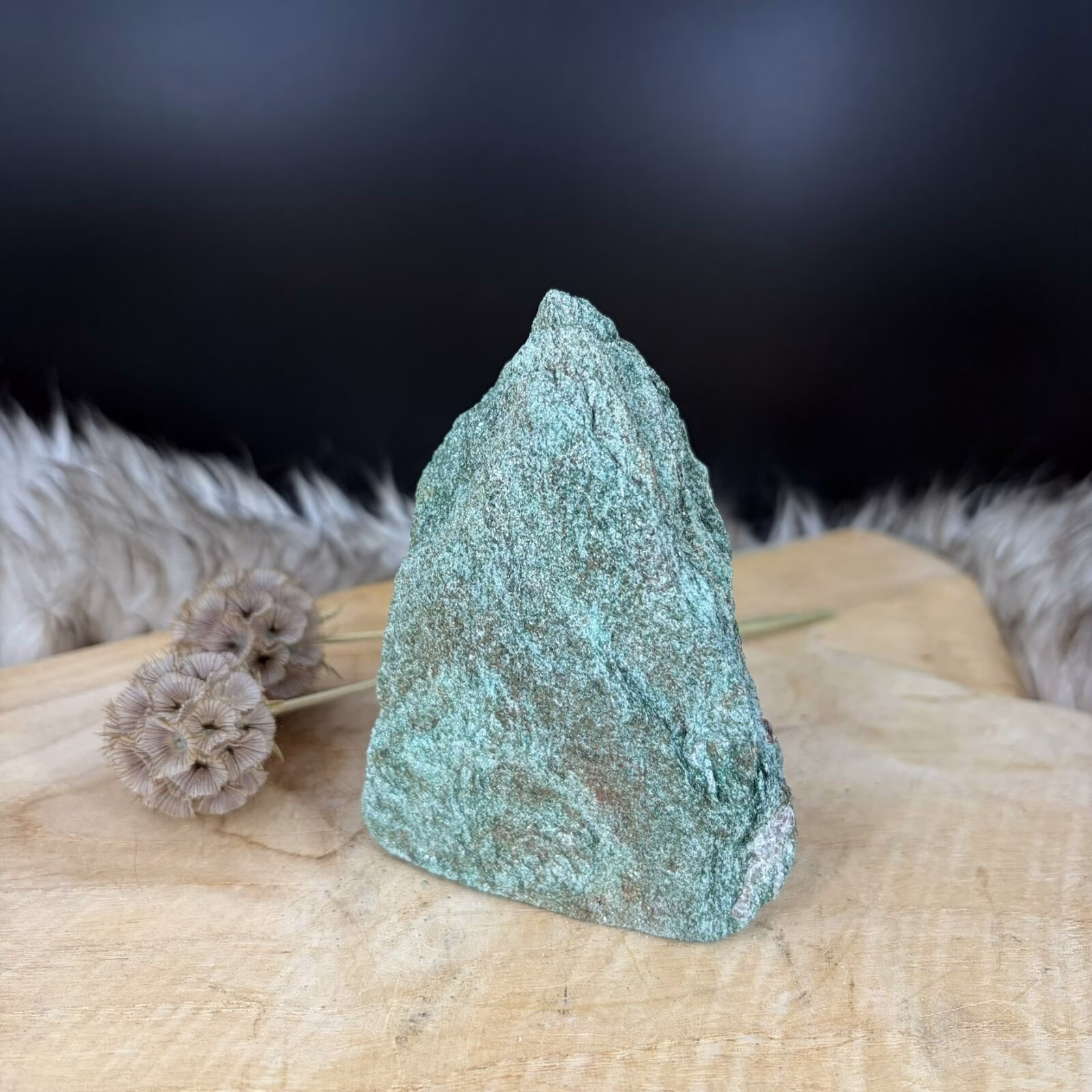 Fuchsiet Freeform van 10 cm hoog met een sprankelende groene kleur, Detail van de glinstering in een Fuchsiet van 506 gram, Zijaanzicht van de 5 cm diepe Freeform Fuchsiet met mica schittering, Groene Fuchsiet op een houten ondergrond in een sfeervol interieur.