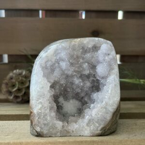 Amethist rus cut base, lichte amethist ruw cut-base op houten oppervlak, ruwe amethist steen met geslepen basis in zonlicht, spirituele amethist decoratie in meditatieruimte, close-up van lichte amethist kristalstructuur, amethist cut-base naast kaarsen en seleniet