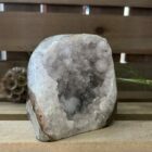 lichte amethist ruw cut-base op houten oppervlak, ruwe amethist steen met geslepen basis in zonlicht, spirituele amethist decoratie in meditatieruimte, close-up van lichte amethist kristalstructuur, amethist cut-base naast kaarsen en seleniet