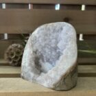 lichte amethist ruw cut-base op houten oppervlak, ruwe amethist steen met geslepen basis in zonlicht, spirituele amethist decoratie in meditatieruimte, close-up van lichte amethist kristalstructuur, amethist cut-base naast kaarsen en seleniet
