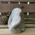 lichte amethist ruw cut-base op houten oppervlak, ruwe amethist steen met geslepen basis in zonlicht, spirituele amethist decoratie in meditatieruimte, close-up van lichte amethist kristalstructuur, amethist cut-base naast kaarsen en seleniet