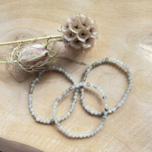 Labradoriet armband 4 mm met iriserende glans, Close-up van labradoriet kralen met blauwe en gouden schakeringen, Labradoriet armband gedragen om de pols in natuurlijk licht, Stapel armbanden met labradoriet als beschermende steen, Labradoriet armband 4 mm in spirituele setting met salie en kristallen