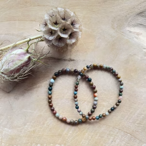 Oceaan jaspis armband 4 mm in zonlicht met zachte kleuren, Pols met oceaan jaspis kralen in mintgroen en beige, Spirituele setting met oceaan jaspis armband en salie, Detail van jaspiskralen met natuurlijke patronen, Oceaan jaspis armband op rustgevend altaar