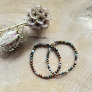Oceaan jaspis armband 4 mm in zonlicht met zachte kleuren, Pols met oceaan jaspis kralen in mintgroen en beige, Spirituele setting met oceaan jaspis armband en salie, Detail van jaspiskralen met natuurlijke patronen, Oceaan jaspis armband op rustgevend altaar