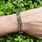 Oceaan jaspis armband 4 mm in zonlicht met zachte kleuren, Pols met oceaan jaspis kralen in mintgroen en beige, Spirituele setting met oceaan jaspis armband en salie, Detail van jaspiskralen met natuurlijke patronen, Oceaan jaspis armband op rustgevend altaar