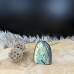 Labradoriet freeform, Labradoriet Sculptuur, Labradoriet Freeform van 5 cm hoog met een blauwe glans, Kleuren in een labradoriet uit Madagaskar van 90 gram, Handzame labradoriet steen voor aurabescherming en rust, Labradoriet op een houten plank die prachtig glinstert in het licht.