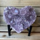 Amethist hart uit Brazilië op zwarte standaard, Paars amethist hart van 837 gram met glinsterende kristallen, Spiritueel amethist hart als woondecoratie en meditatiesteen, Hartvormige amethist steen met natuurlijke kristalstructuur, Uniek amethist hart 9 x 14 x 3 cm geleverd met standaard