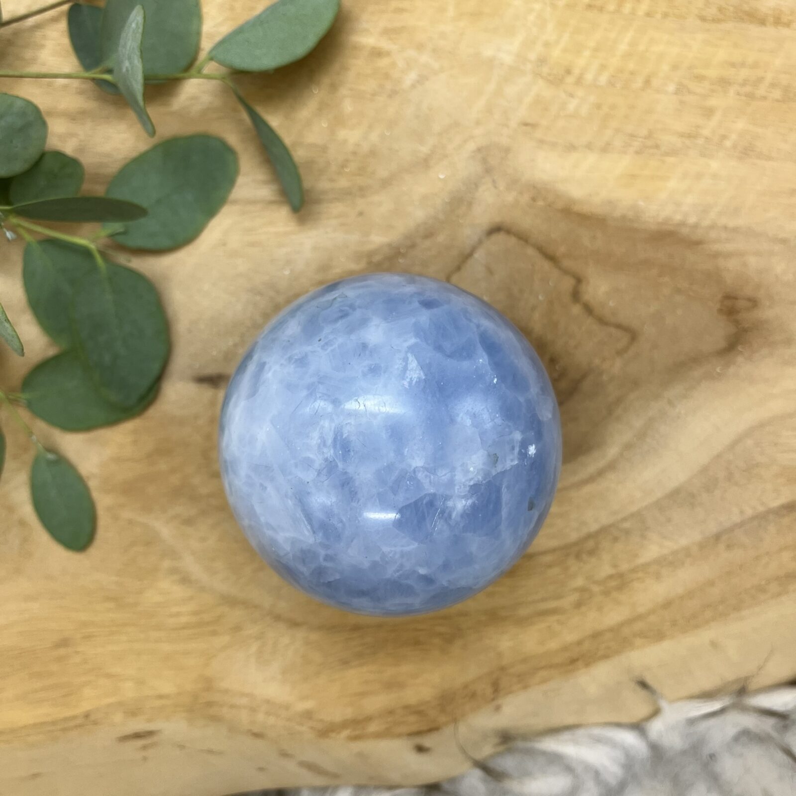 Blauwe calciet bol met gemêleerd patroon van wit en lichtblauw, Glanzende calciet bol van 462 gram met natuurlijke kleurschakeringen, Sierbol van blauwe calciet met wolkachtig gemêleerd effect, Calciet kristalbol van 8 cm doorsnee met zachte blauwe tinten, Handgeslepen blauwe calciet bol met marmerachtig patroon, Decoratieve edelsteen bol van calciet met rustgevende blauwe nuances