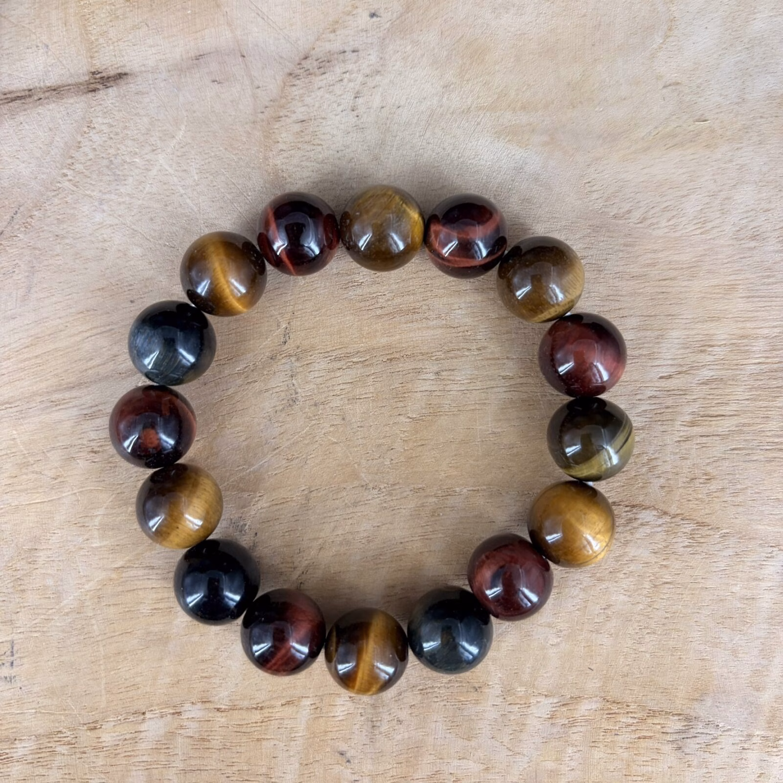 Drie kleuren tijgeroog armband, Tijgeroog tricolor armband, Tijgeroog tricolor armband met grote kralen van 12 mm in goud, blauw en rood, stoere edelsteen armband met 12 mm tijgeroog kralen voor bescherming en moed, close-up van een robuuste tricolor tijgeroog armband met prachtige zijdeglans, handgemaakte armband van 45 gram tijgeroog mix voor meer zelfvertrouwen en daadkracht, spirituele tijgeroog armband met grove kralen die helpt bij balans en focus, detailfoto van een tijgeroog tricolor 12 mm armband met unieke natuurlijke kleurpatronen.