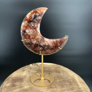 Fire Quartz Moon op Standaard 514 gram, vuurkwarts maan met rode hematietaders, Fire Quartz Moon op houten tafel bij kaarslicht, detail van hematoïde kwarts in Fire Quartz Moon, Fire Quartz Moon op goudkleurige standaard in woonkamer, Fire Quartz Moon als spirituele decoratie bij altaar.