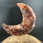 Fire Quartz Moon op Standaard 514 gram, vuurkwarts maan met rode hematietaders, Fire Quartz Moon op houten tafel bij kaarslicht, detail van hematoïde kwarts in Fire Quartz Moon, Fire Quartz Moon op goudkleurige standaard in woonkamer, Fire Quartz Moon als spirituele decoratie bij altaar.