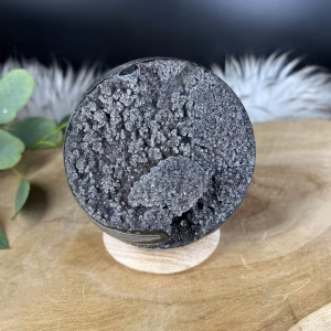 Zwarte Amethist Bol, donkere amethist geode, zwarte kristallen met hematiet, Zwarte Amethist Bol 670 gram, diameter 9 cm, amethist bol op houten houder, Zwarte Amethist Bol Uruguay, beschermende en aardende steen, fonkelende zwarte kristallen, Zwarte Amethist Bol tegen angst en stress, Trigonaal kristalsysteem