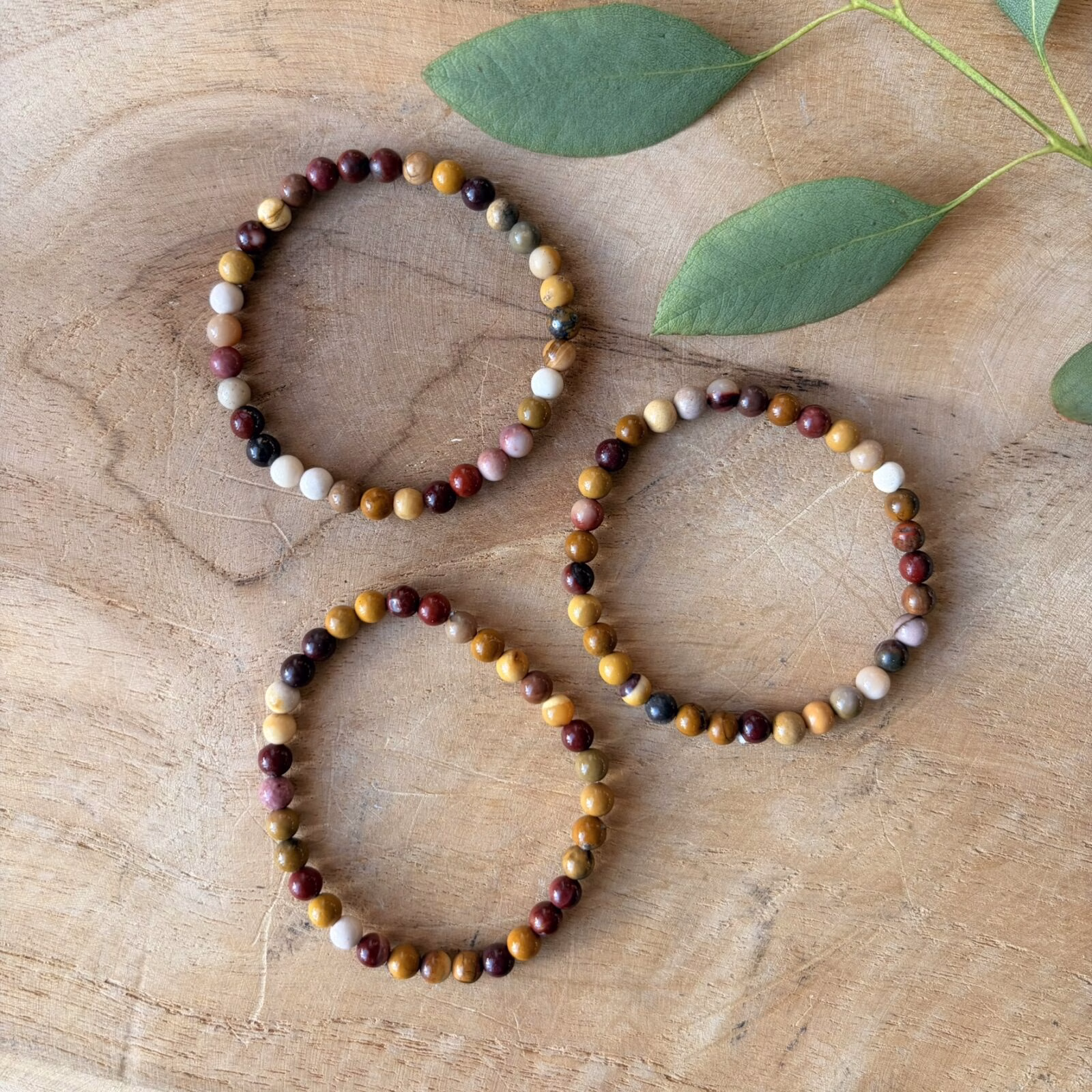 Mookaiet jaspis kinderarmband met 4 mm kralen in warme herfstkleuren zoals geel en rood, detailopname van de kleurrijke mookaiet jaspis kralen van een elastisch kinderarmbandje, mookaiet jaspis kinderarmband gedragen om een kleine pols voor extra moed en energie, kleurrijke edelsteen armband van mookaiet jaspis speciaal voor kinderen, mookaiet jaspis kinderarmband liggend op een lichte ondergrond die de natuurlijke variatie van de stenen toont, handgemaakte kinderarmband met mookaiet jaspis kralen voor een vrolijke en beschermende uitstraling.