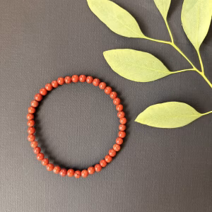 Rode Jaspis armband 4 mm, Subtiele Rode Jaspis armband met fijne 4 mm kralen in een diepe aardse kleur, detailopname van een elastische armband met kleine rode jaspis kralen voor dagelijkse kracht, Rode Jaspis armband 4 mm gedragen om de pols voor een elegante en aardende uitstraling, verfijnde edelsteen armband van rode jaspis met 4 mm kralen van hoge kwaliteit, Rode Jaspis armband 4 mm liggend naast een op- en ontlaadsetje van Natuursteentje, handgemaakte armband met kleine rode jaspis kralen van 4 mm die stabiliteit en focus uitstralen.