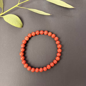 Rode Jaspis armband 6 mm, Rode Jaspis armband met 6 mm kralen in een dieprode en aardse kleur, detailopname van de gladde rode jaspis kralen van een elastische armband, Rode Jaspis armband 6 mm gedragen om de pols voor extra stabiliteit en kracht, krachtige edelsteen armband van rode jaspis met een gewicht van 12 gram, Rode Jaspis armband 6 mm liggend op een natuurlijke ondergrond voor een aardse sfeer, handgemaakte armband met rode jaspis kralen van 6 mm die vitaliteit en daadkracht uitstralen.