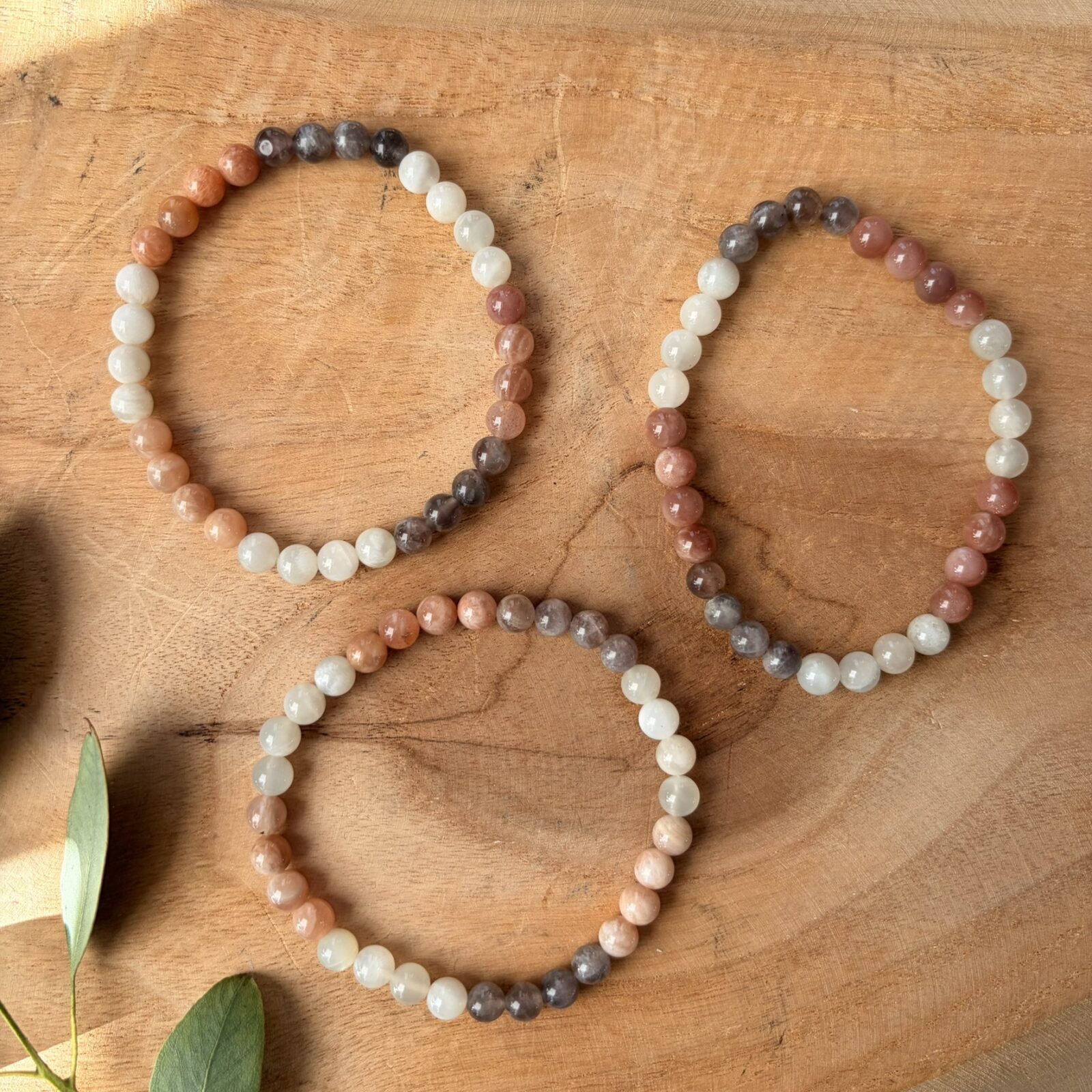 'Maansteen mix armband 6 mm, Gepolijste maansteen mix armband met 6 mm kralen in zachte tinten grijs en wit, close-up van een elastische maansteen armband met natuurlijke kleurnuances van crème tot zilver, maansteen mix armband 6 mm gedragen om een pols voor een rustige uitstraling, collectie maansteen armbanden met 6 mm kralen die de natuurlijke glans van de steen tonen, maansteen mix armband 6 mm liggend op een houten ondergrond voor een natuurlijke sfeer, detailopname van de gladde 6 mm kralen van een maansteen mix armband bij daglicht, maansteen mix armband 6 mm naast een op- en ontlaadsetje van Natuursteentje, handgemaakte maansteen armband met kralen van 6 mm die de zachte energie van de maansteen weerspiegelen.