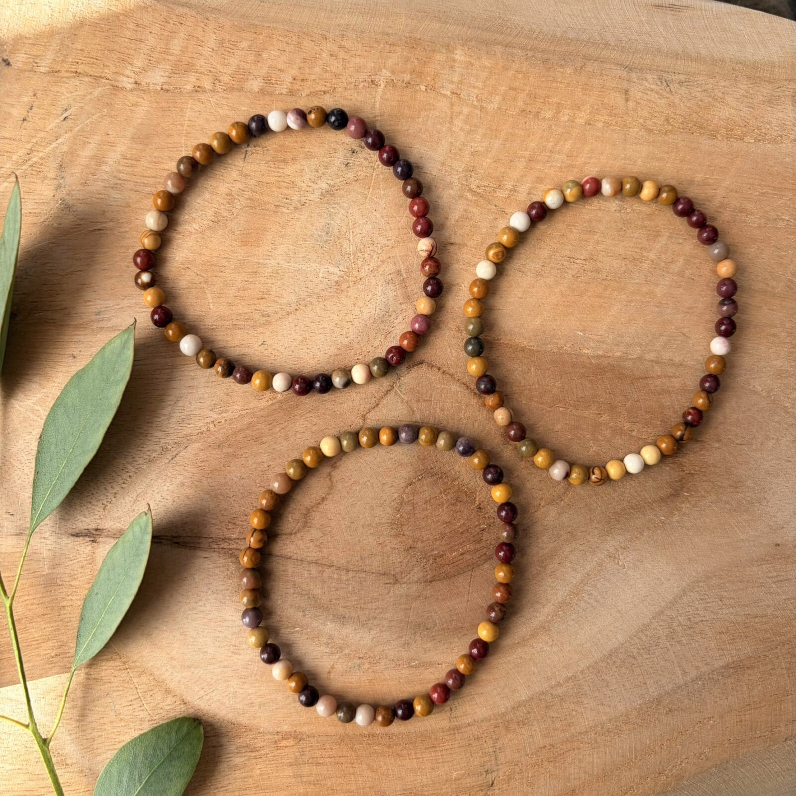 Subtiele Mookaiet Jaspis armband met kleine 4 mm kralen in vrolijke geel- en roodtinten, detailopname van een elastische armband met verfijnde mookaiet jaspis kralen van hoge kwaliteit, Mookaiet Jaspis armband 4 mm gedragen om de pols voor een elegante en kleurrijke uitstraling, verfijnde edelsteen armband van mookaiet jaspis met 4 mm kralen voor nieuwe energie, Mookaiet Jaspis armband 4 mm liggend op een lichte ondergrond die de natuurlijke patronen toont, handgemaakte armband met kleine mookaiet jaspis kralen van 4 mm die levenslust en rust uitstralen.