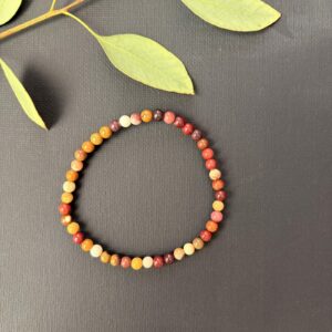Subtiele Mookaiet Jaspis armband met kleine 4 mm kralen in vrolijke geel- en roodtinten, detailopname van een elastische armband met verfijnde mookaiet jaspis kralen van hoge kwaliteit, Mookaiet Jaspis armband 4 mm gedragen om de pols voor een elegante en kleurrijke uitstraling, verfijnde edelsteen armband van mookaiet jaspis met 4 mm kralen voor nieuwe energie, Mookaiet Jaspis armband 4 mm liggend op een lichte ondergrond die de natuurlijke patronen toont, handgemaakte armband met kleine mookaiet jaspis kralen van 4 mm die levenslust en rust uitstralen.