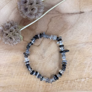 Toermalijnkwarts splitarmband, Toermalijnkwarts armband, Toermalijnkwarts splitarmband met heldere kwarts en zwarte toermalijn naalden, elastische armband van toermalijnkwarts voor bescherming en reiniging, close-up van een edelsteen armband met transparante stenen en zwarte inclusies, handgemaakte armband met natuurlijke toermalijnkwarts splitstenen, spirituele toermalijnkwarts armband die negatieve energie omzet in positieve, detail van unieke toermalijnkwarts kristallen met krachtige zwarte lijnen erin.