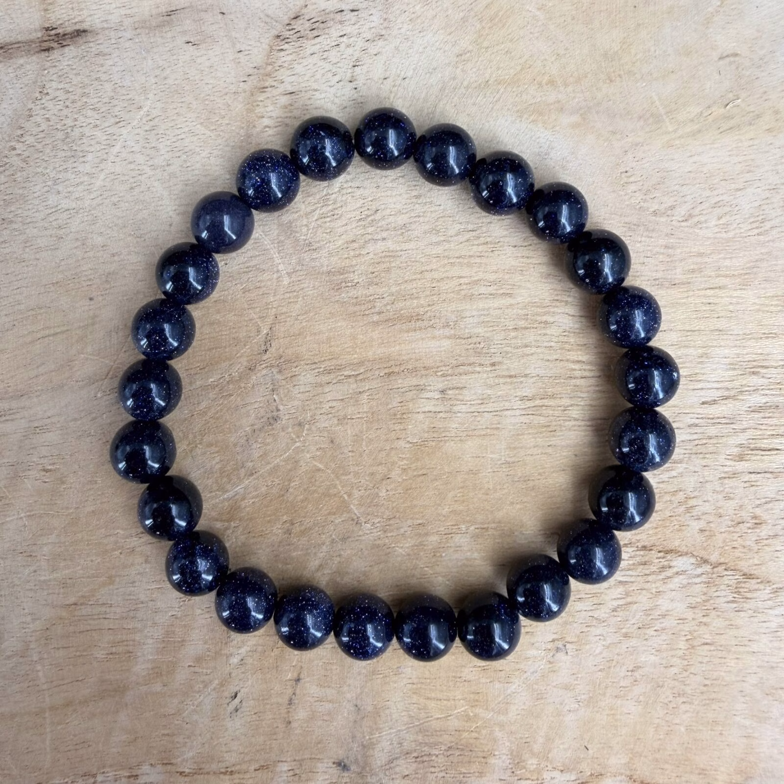 Blauwe goudsteen armband 8 mm, Blauwe goudsteen armband, Blauwe goudsteen armband met opvallende fonkelende kralen van 8 mm, elastische armband met schitterende donkerblauwe goudsteen voor ambitie en kracht, close-up van een 8 mm kralen armband met glinsterende sterrenhemel effect, handgemaakte armband van blauwe goudsteen met diepe nachtblauwe glans, stevige blauwe goudsteen armband met ronde kralen van 8 millimeter, detailfoto van de prachtige glitters in een blauwe goudsteen edelsteen armband.