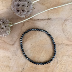 Hematiet armband 4 mm, Hematiet armband, Hematiet armband met kleine metallic grijze kralen van 4 mm voor een sterke aarding, subtiele edelsteen armband van 4 mm hematiet die helpt bij zelfvertrouwen en wilskracht, close-up van een glanzende grijze hematiet armband van hoge kwaliteit, handgemaakte armband met 4 mm hematiet kristallen tegen negatieve energie, spirituele hematiet armband met kleine kralen die beschermt tegen prikkels van buitenaf, detailfoto van een hematiet 4 mm armband met een stoere metallic glans.
