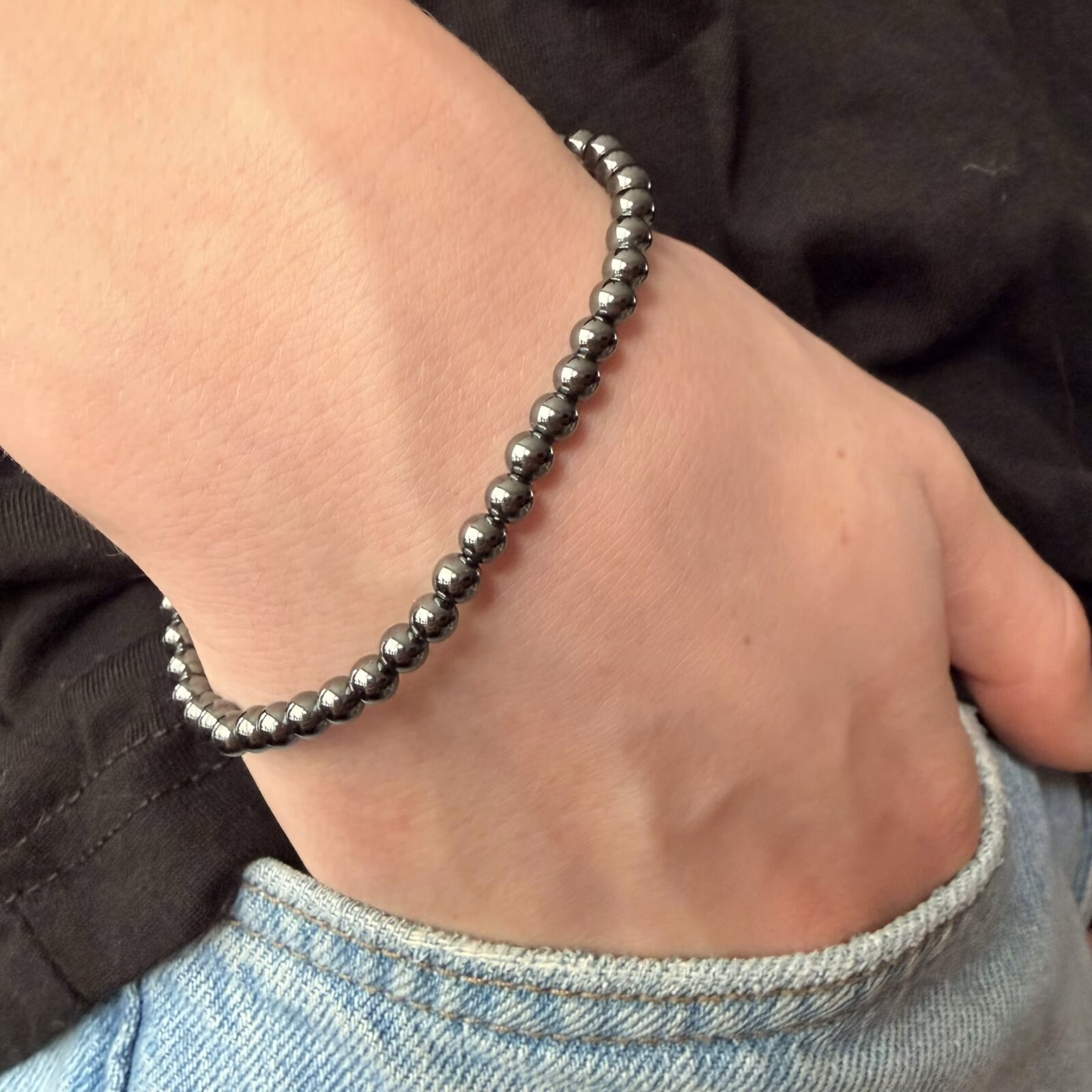 Hematiet armband 4 mm, Hematiet armband, Hematiet armband met kleine metallic grijze kralen van 4 mm voor een sterke aarding, subtiele edelsteen armband van 4 mm hematiet die helpt bij zelfvertrouwen en wilskracht, close-up van een glanzende grijze hematiet armband van hoge kwaliteit, handgemaakte armband met 4 mm hematiet kristallen tegen negatieve energie, spirituele hematiet armband met kleine kralen die beschermt tegen prikkels van buitenaf, detailfoto van een hematiet 4 mm armband met een stoere metallic glans.