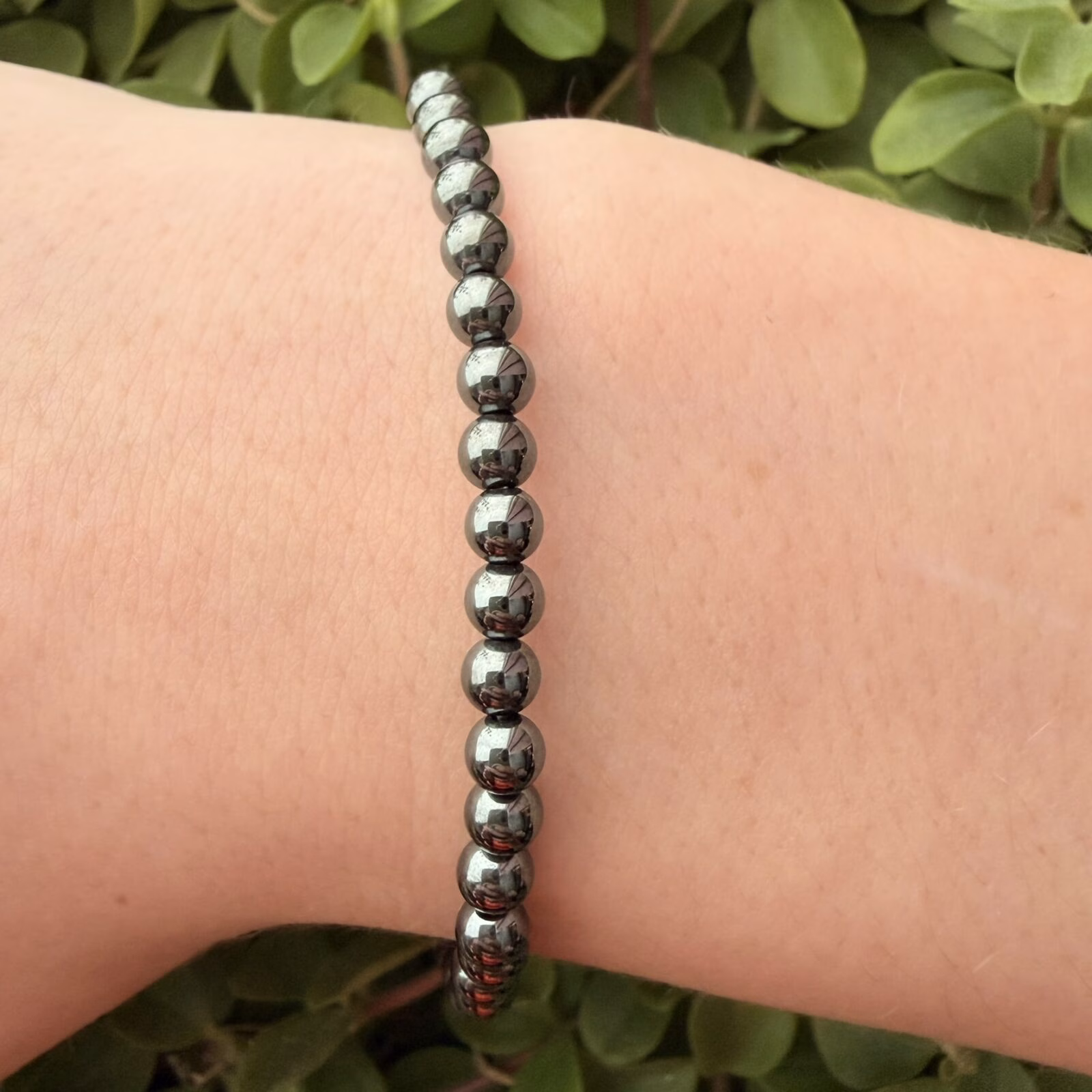 Hematiet armband 4 mm, Hematiet armband, Hematiet armband met kleine metallic grijze kralen van 4 mm voor een sterke aarding, subtiele edelsteen armband van 4 mm hematiet die helpt bij zelfvertrouwen en wilskracht, close-up van een glanzende grijze hematiet armband van hoge kwaliteit, handgemaakte armband met 4 mm hematiet kristallen tegen negatieve energie, spirituele hematiet armband met kleine kralen die beschermt tegen prikkels van buitenaf, detailfoto van een hematiet 4 mm armband met een stoere metallic glans.