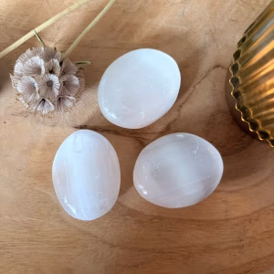 Seleniet steen, Seleniet Palmsteen, Seleniet palmsteen bij kaarslicht, Seleniet palmsteen 30 gram voor rust en zuivering, witte satijnachtige edelsteen bij Natuursteentje, handgeselecteerde Seleniet kopen voor helderheid, spirituele werking Seleniet tegen overprikkeling, edelsteen combinatie met Amethist en Bergkristal, unieke witte palmsteen webshop Natuursteentje.