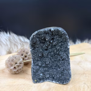 Vooraanzicht van een glanzende zwarte amethist cut-base van 336 gram met intense schittering. Detail van de diepe donkere kristallen van de zwarte amethist. Zijaanzicht van de compacte amethist zwart van 8 centimeter hoog. De vlakke onderkant van de zwarte amethist cut-base voor een stabiele stand. De zwarte amethist getoond als uniek mineraal en krachtige beschermer voor in huis.