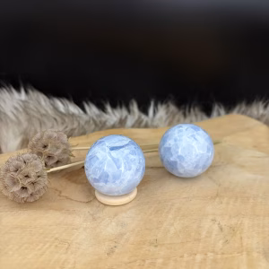 Blauwe calciet bol 4 cm op houten tafel, blauwe calciet bol 100 gram madagaskar, edelsteen bol blauw 4 cm, calciet kristal rust, blauwe steen keelchakra, blauwe calciet kreeft, geslepen edelsteen bol, blauwe calciet tegen stress