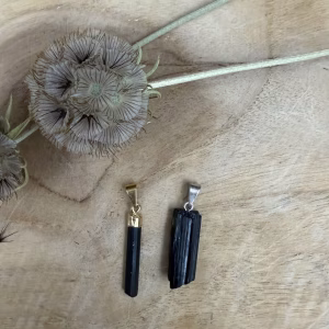 Ruwe Zwarte Toermalijn Hanger met een subtiel goud plated ringetje op een witte ondergrond, Ruwe Zwarte Toermalijn Hanger met een subtiel silver plated ringetje op een houten ondergrond.