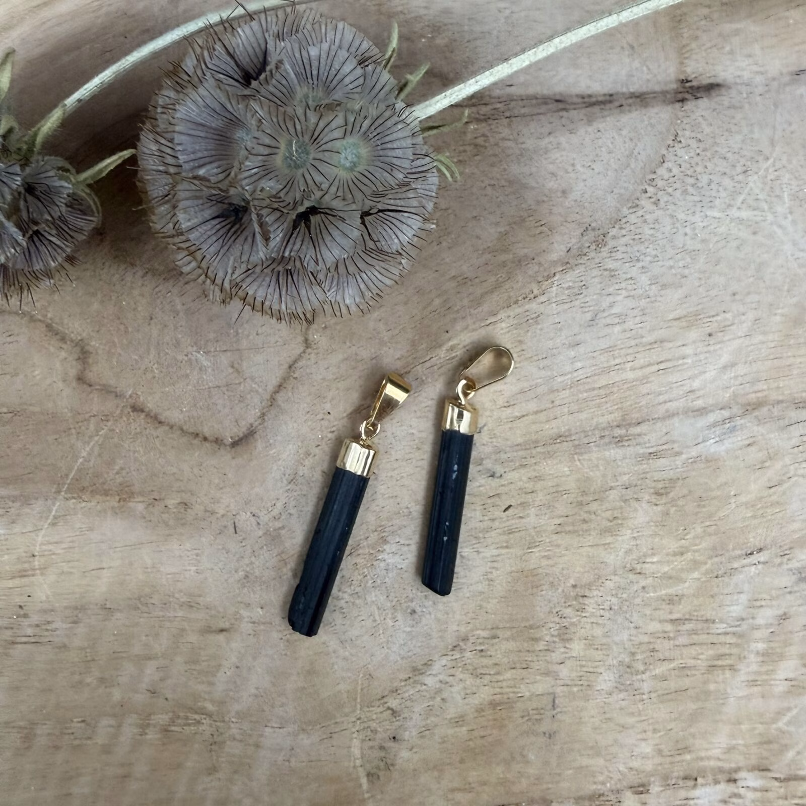 Ruwe Zwarte Toermalijn Hanger met een subtiel goud plated ringetje op een witte ondergrond.