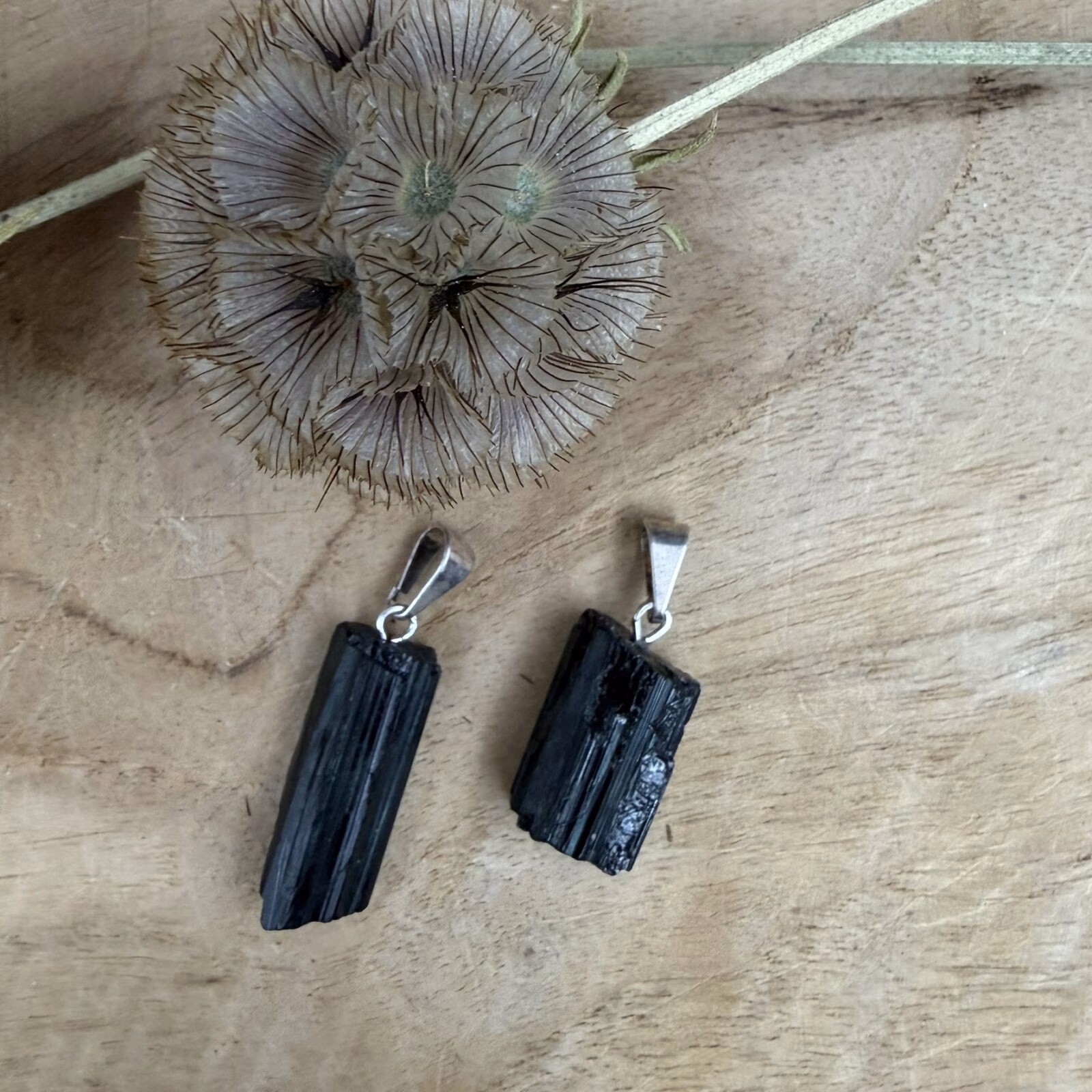 Ruwe Zwarte Toermalijn Hanger met een subtiel silver plated ringetje op een houten ondergrond.