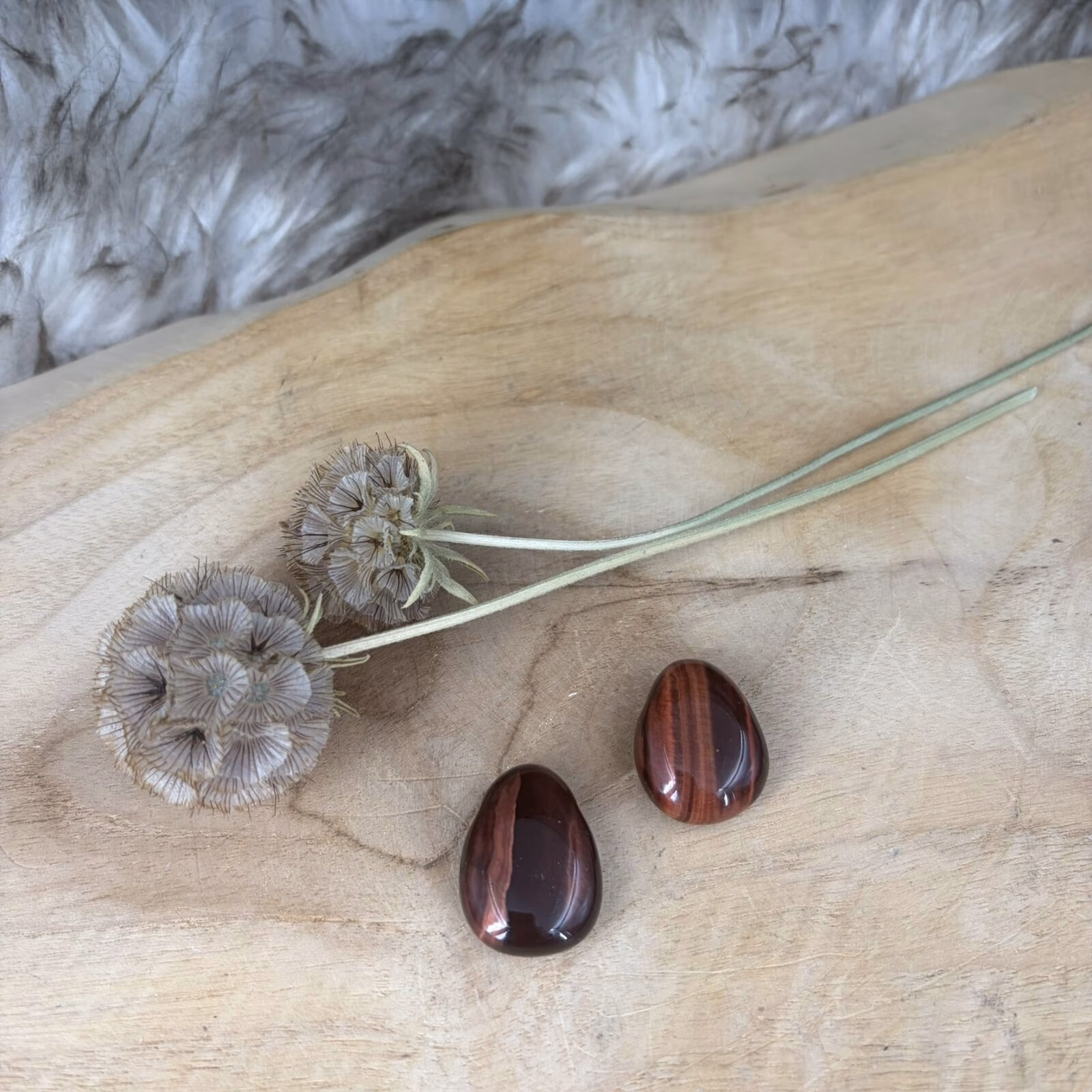 Een doorboorde Rode Tijgeroog hanger met roodbruine glans op een houten ondergrond