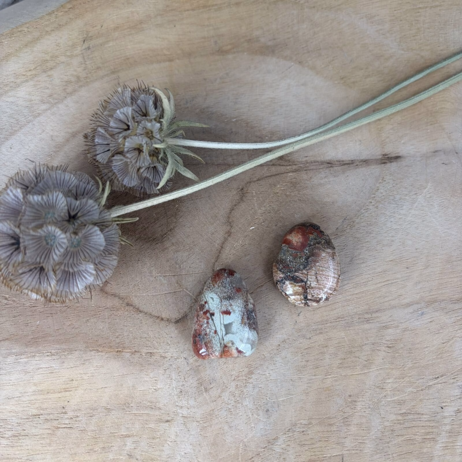 Een doorboorde Poppy Jaspis hanger met rood bloempatroon op een houten ondergrond